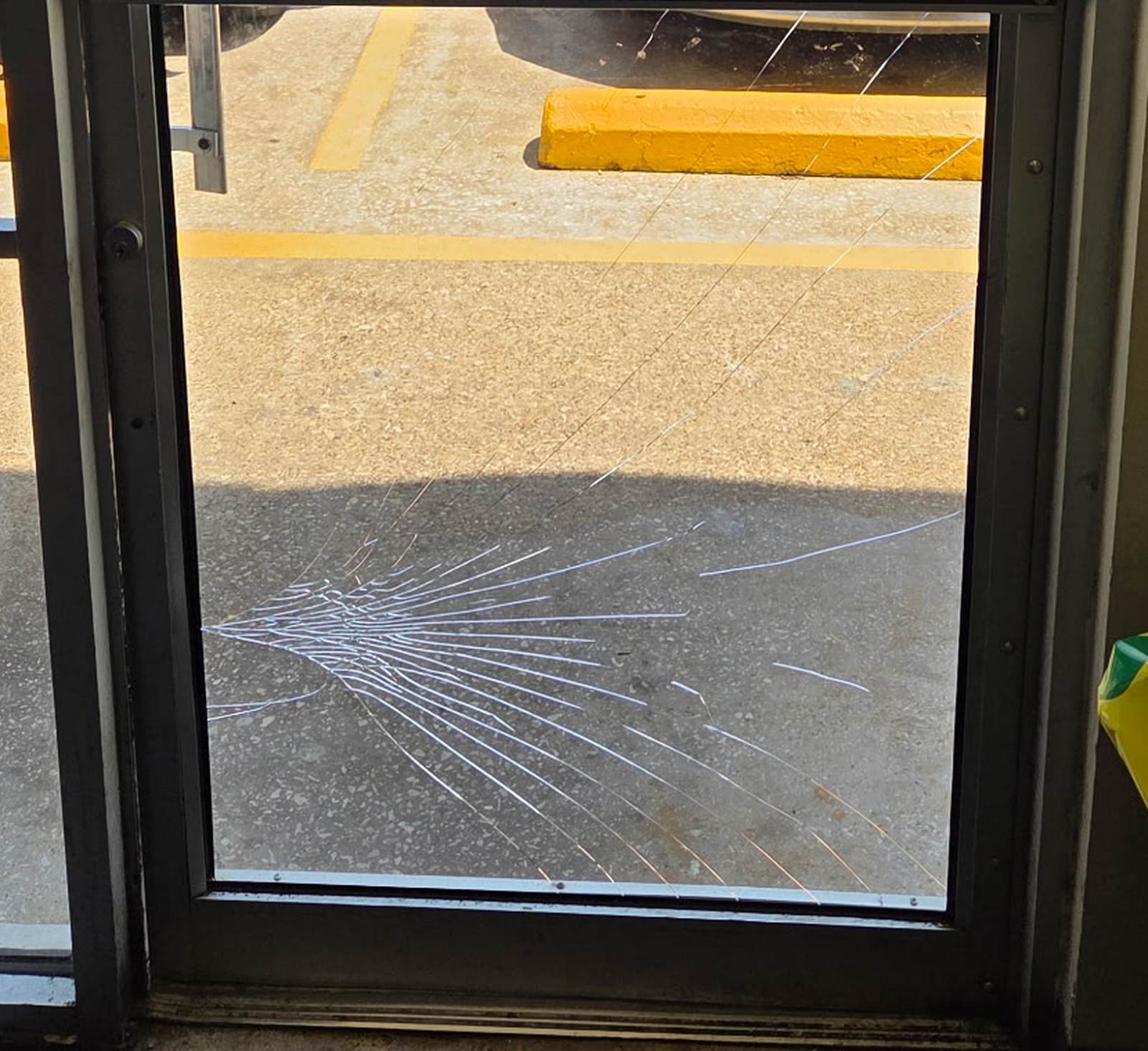 Cracked lower glass panel in a commercial storefront door.